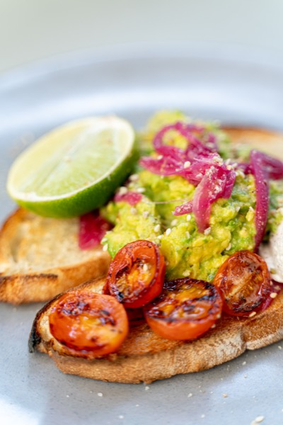 Smashed avocado on toast with roast tomatoes and pickled onion