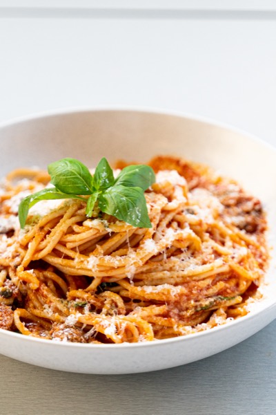 Spaghetti topped with parmesan and fresh basil